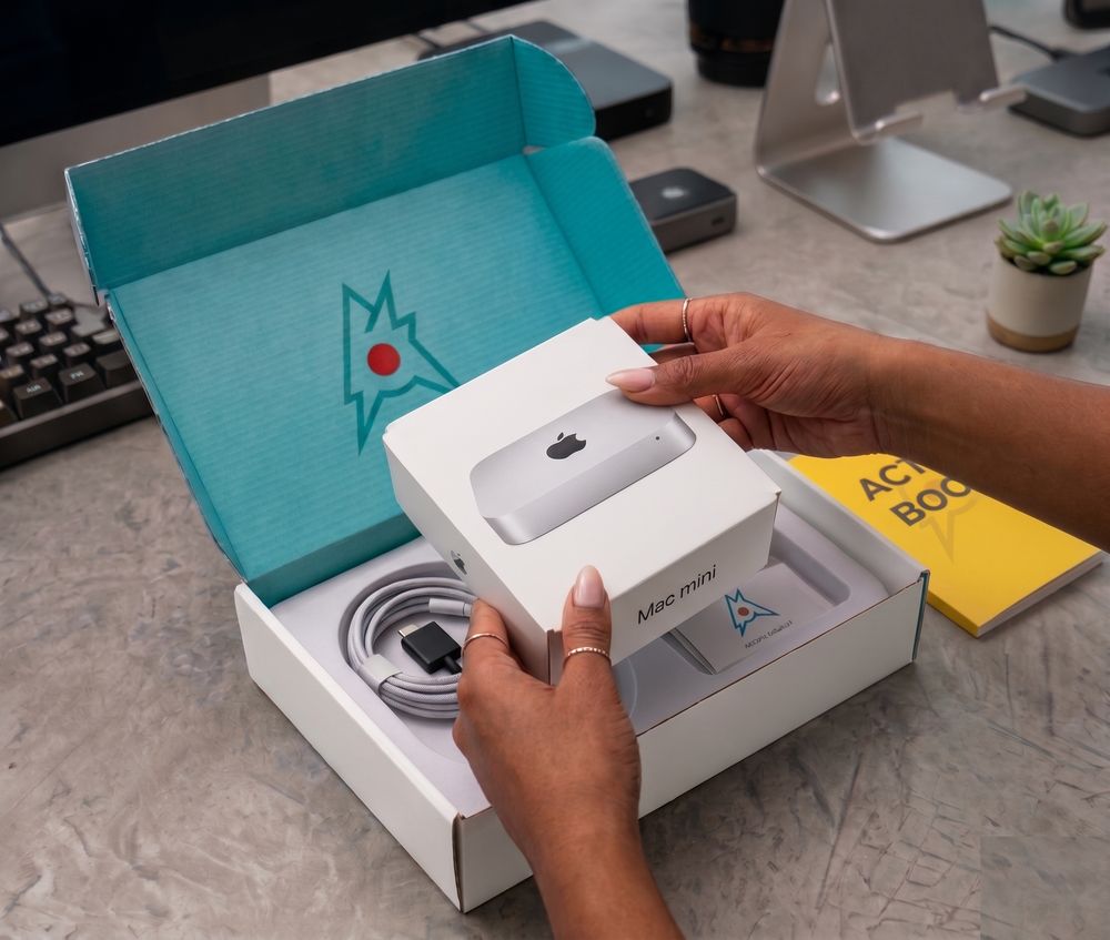 An opened Action Box revealing what's inside — the Mac mini Action Cell, accessories, and the Action Book field guide.